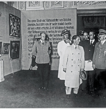 Hitlers Deģeneratīvās mākslas izstādē Minhenē. No Hitlera pa labi – profesors Cīglers un Heinrihs Hofmans, pa kreisi Haušs, Gebelss u. c. 1937. gada 19. jūlijs.