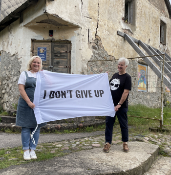 Ieva un Dainis Grozas pie Lēdurgas kroga ieejas ar plakātu, kura teksts angļu valodā vēsta “Es nepadošos”. Esot aizgūts no mākslinieka Kristiana Brektes oriģināla.