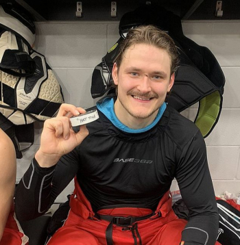 Smaidīgais Eduards Tralmaks pozē ar ripu pēc spēles, kurā viņš pirmo reizi savā profesionālajā karjerā Ziemeļamerikā guva trīs vārtus.