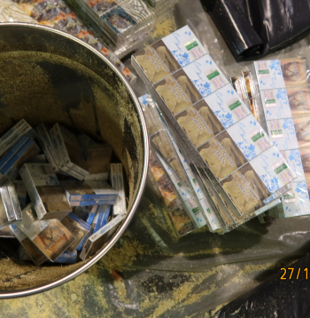 Spaiņos sabērtas zāģskaidas, bet zem tām — dažādu marku cigaretes.