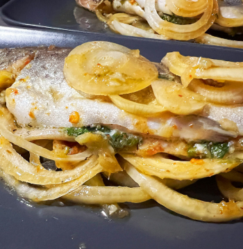 Cepta varavīksnes forele apelsīnu–sojas–medus marinādē ar sīpoliem.