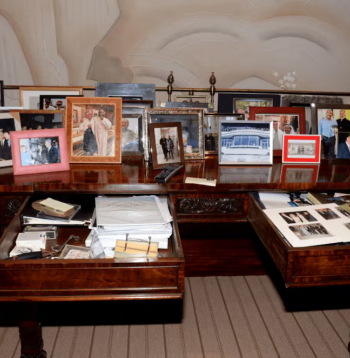 Epstīna faili. 
Fotogrāfijā redzams galds ar atvērtu atvilktni, kur atrodas kaudzīte ar fotogrāfijām, tai skaitā foto, kur Tramps ir kopā ar bikini tērptām sievietēm. Šis Trampa foto uzņemts pirms viņš kļuva par prezidentu.