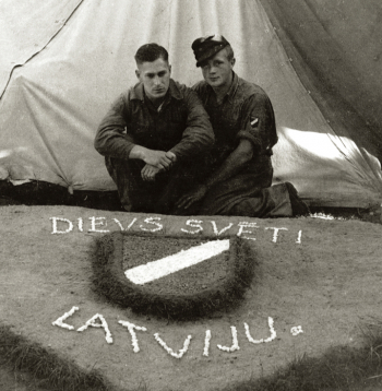 Internētie latviešu leģionāri pie pašdarināta rotājuma – latviešu leģiona vairodziņa. Ēkšes – Rennesletes nometne, 1945. gada
vasara.