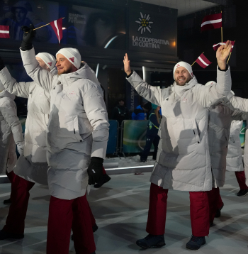 Latvijas karognesējs 2026. gada ziemas olimpiskajās spēlēs, hokejists Kaspars Daugaviņš (no labās) un Latvijas delegācijas sportisti 2026. gada Milānas un Kortīnas ziemas olimpisko spēļu atklāšanas ceremonijā "San Siro" stadionā Milānā, Itālijā.