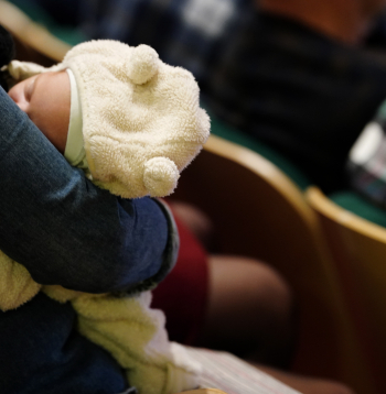 Zīdainis vecāka rokās.