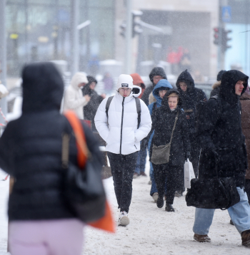 Cilvēki sniegputeņa laikā Merķeļa ielā.