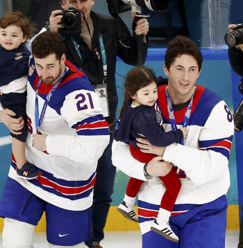 ASV izlases hokejisti Dilans Larkins (no kreisās) un Zaks Verenskis ar traģiski bojā gājušā bijušā komandas biedra Džonija Gudro bērniem pirms čempionu kopbildes.