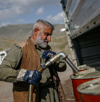 Tirgotājs pie Bašmahas robežšķērsošanas punkta 2026. gada 11. martā sūknē benzīnu no Irānas degvielas tankkuģiem tālākpārdošanai.