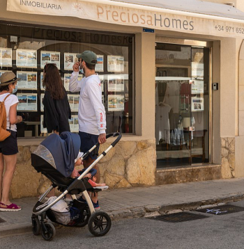 Tūristi Maļorkas (Spānija) pilsētā Kamposā pēta nekustamo īpašumu firmas skatlogā izlikto mājokļu piedāvājumu.