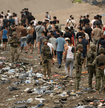 Pie žoga netālu no sadursmju vietas pie Fnidekas, uz Marokas un Spānijas robežas, 2026. gada 31. jūlijā pulcējušies cilvēki. Tūkstošiem migrantu nakts laikā no Marokas šķērsoja robežu un iekļuva Spānijas Ziemeļāfrikas anklāvā Seutā, 31. jūlijā pavēstīja policijas avots. 