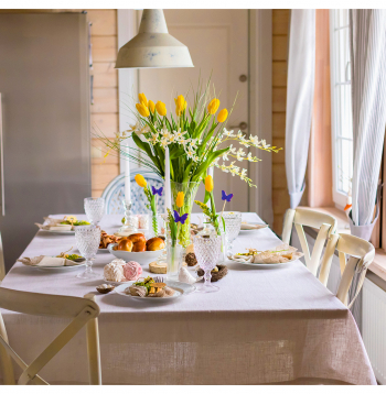 Lieldienu galdu klāj ar gaišu galda segu un piemērotiem traukiem