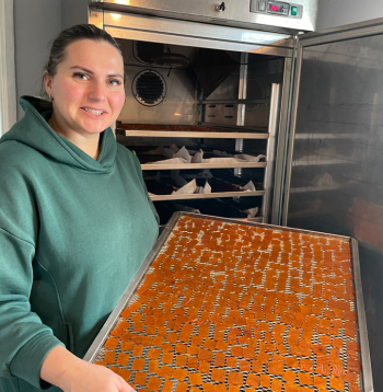 Dienu un nakti mājas virtuvē darbojas žāvētava. Attēlā: saimniece no žāvētavas izņem kārtējo gatavo konfekšu plāti.