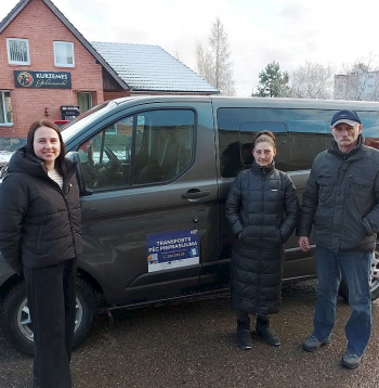 Kad pierod un iepazīst, visi ir apmierināti – par jauno pārvietošanās iespēju laukos saka pārvadātāju pārstāve Elīna Kramēna (no kreisās) un pasažieri no Vānes Kristīne Mitrofanova un Ivans Zvirs. Fonā – busiņš, ar kuru tiek pārvadāti pasažieri.