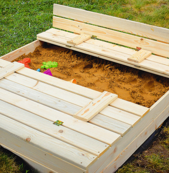 Smilškaste ar vāku, kas pārtop par soliņu.