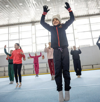 Kijivā un citās Ukrainas pilsētās ir elektroenerģijas un apkures pārtraukumi pēc Krievijas uzbrukumiem kritiskajai infrastruktūrai. Attēlā: skolas vingrošanas zālē gaisa temperatūra nepārsniedz +5 grādus, tāpēc meitenes vingrinājumus veic, uzvilkušas siltas zeķes, cimdus, ziemas cepures.