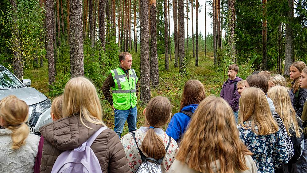 Daugmales skolēni ar interesi klausās LVM darbinieku stāstos par norisēm mežā.