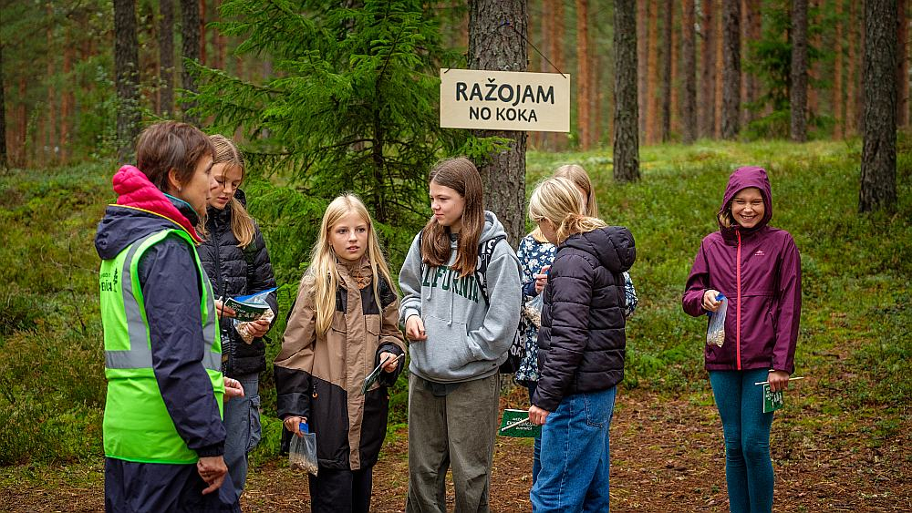 Daugmales skolēni ar interesi klausās LVM darbinieku stāstos par norisēm mežā.