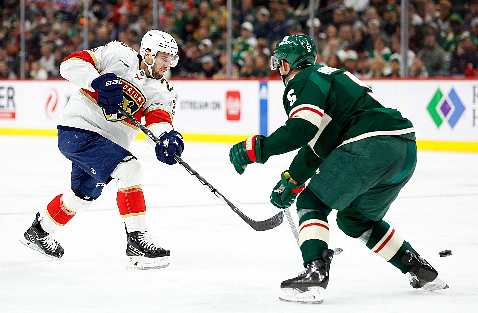 Uvis Balinskis (no kreisās) izdara metienu mačā pret Minesotas "Wild". Balinskis ir 28. Latvijas hokejists, kurš aizvadījis kaut vienu NHL maču.