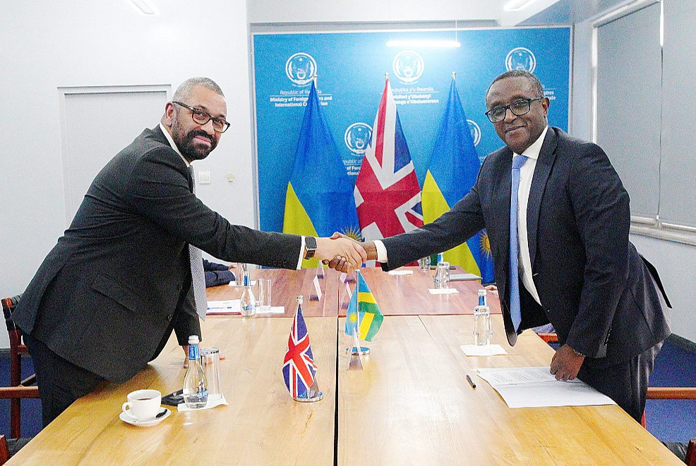 Lielbritānijas iekšlietu ministrs Džeimss Kleverlijs (no kreisās) un Ruandas ārlietu ministrs Vinsents Biruta, Ruandas galvaspilsētā Kigali otrdien parakstot jaunu migrācijas līgumu.