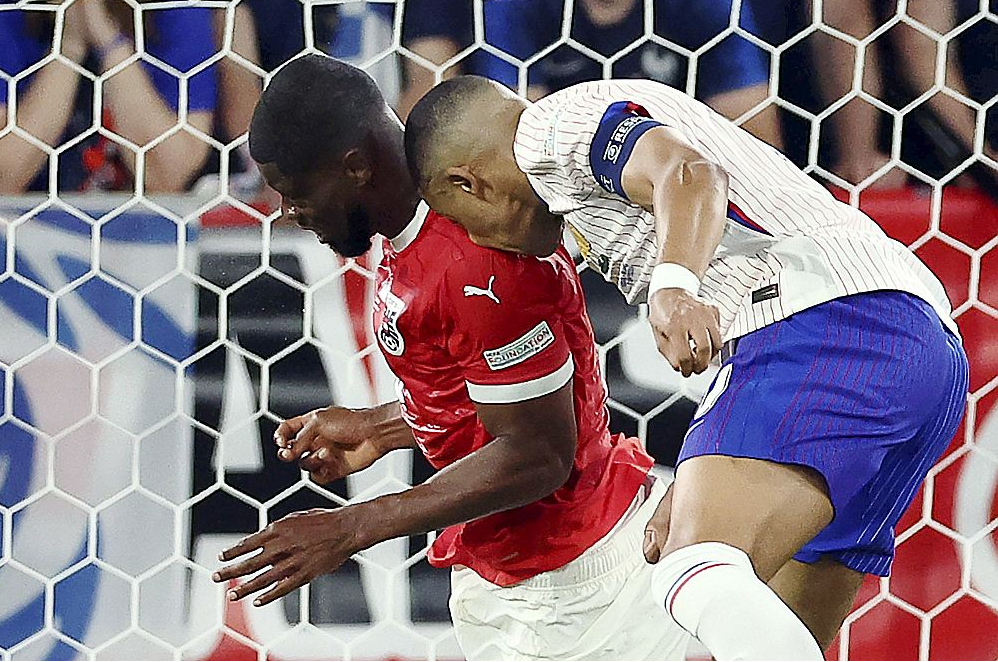 Francijas izlases kapteinis Kilians Mbapē spēlē ar Austriju salauza degunu pret Kevina Danso plecu.