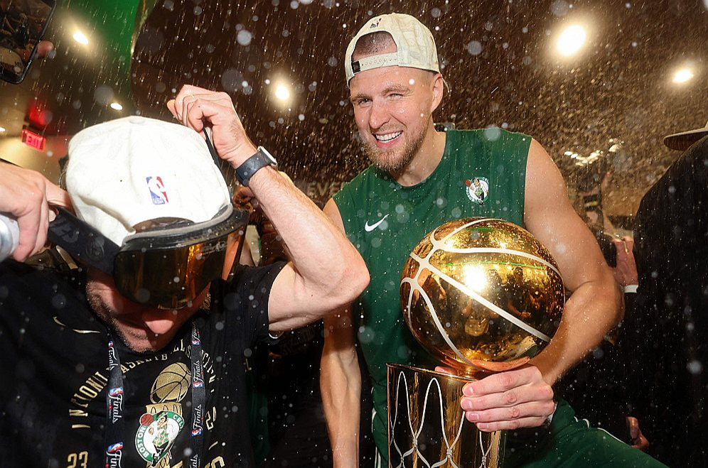 Kristaps Porziņģis ar NBA čempionu kausu rokās izbauda šampanieša šaltis Bostonas "Celtics" komandas ģērbtuvē.
