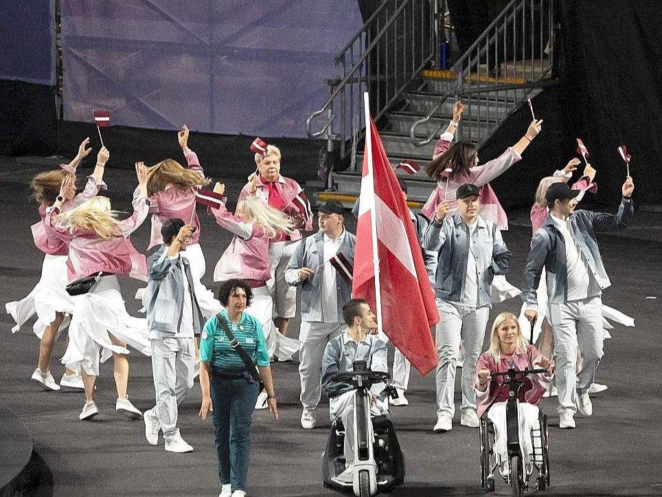 Latvijas karogs atklāšanas ceremonijā plīvoja Diānas Krūmiņas un Riharda Snikus rokās.
