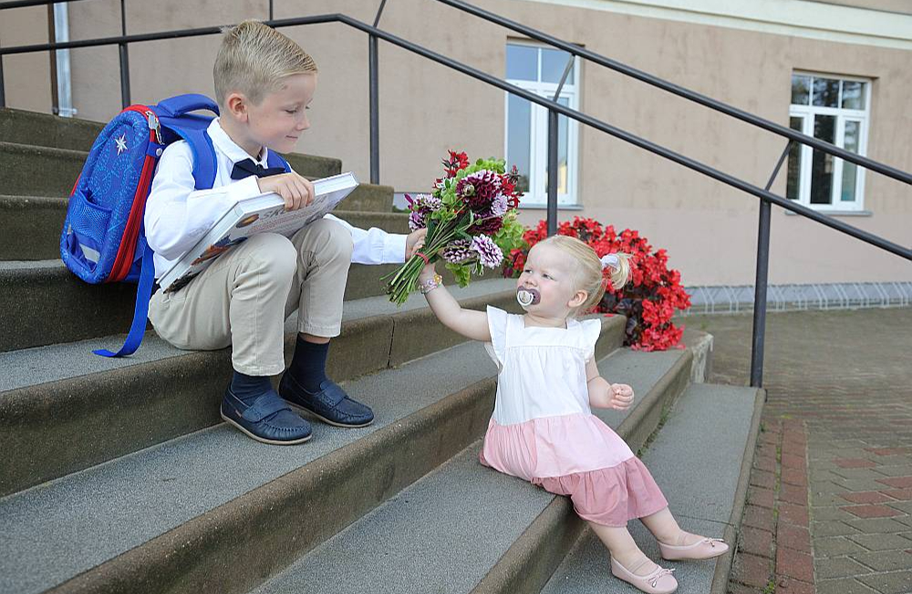 Pirmā skolas diena šodien ir arī "Latvijas Mediju" darbinieces Ineses Baltmanes dēlam Rūdolfam, kurš mācīsies Baldones vidusskolas 1. klasē. Rūdolfs jau ielauzījies lasīšanā, bet ar lielu prieku arī klausās, kad viņam lasa priekšā. Īpaši viņam patīk grāmatas par dzīvniekiem, piemēram, Džeralda Darela "Mana ģimene un citi zvēri". Kā saka mamma Inese – ja Rūdolfam ļautu, tad arī viņu māja būtu pilna ar kukaiņiem, ķirzakām un citiem dzīvniekiem, tāpat kā tas reiz bija mazajam Džeraldam Grieķijas salā Korfu. Arī Rūdolfa mazajai māsai Alisei septembrī sākas jauna dzīve – viņa turpmāk katru darbadienu dosies uz Baldones pirmsskolas izglītības iestādi "Vāverīte".