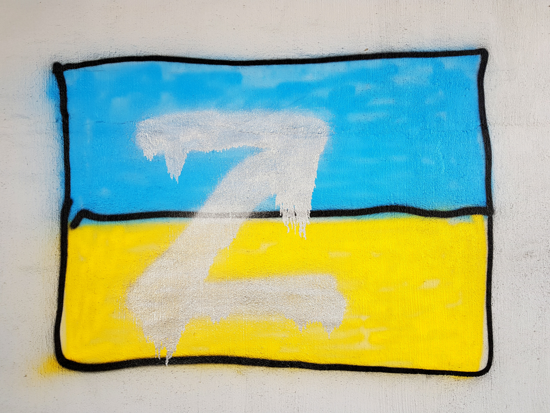 Ukrainas karogs, kuram pāri uzkrāsots Z burts. Zem tilta, kur brauc 7. tramvajs, Mazā Krasta iela, Rīga.