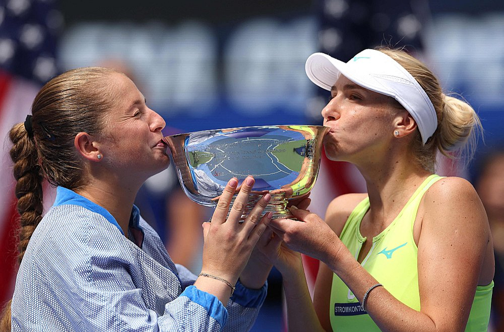 Aļona Ostapenko (no kreisās) un Ludmila Kičenoka ar ASV atklātā čempionāta dāmu dubultspēļu turnīra galveno trofeju.
