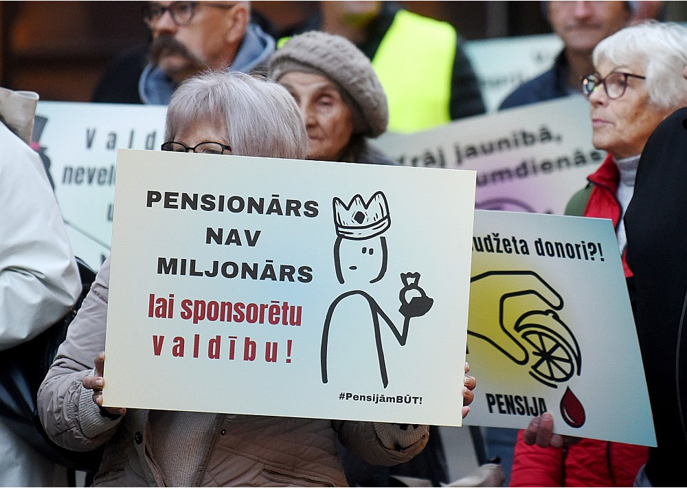 Ministrija atgādina, ka no 2025. gada 1. janvāra tiek ieviesta divu pakāpju iedzīvotāju ienākuma nodokļa likme – 25,5% ienākumiem līdz 105 300 eiro gadā (8775 eiro mēnesī), 33% – ienākumiem virs šīs robežas. Strādājošiem pensionāriem viņu mēneša kopējais neapliekamais minimums būs 1000 eiro mēnesī. Attēlā: pensionāru un strādājošo protesta gājiens šā gada oktobrī.