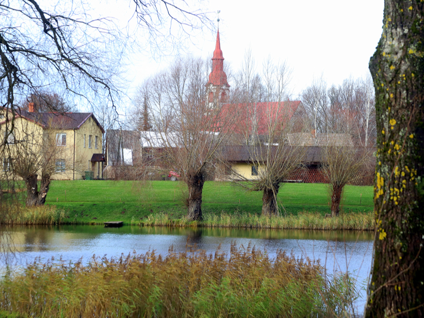 Aiz Dzirnavu ezera pakalna panorāmā redzama Lēdurgas Ev. luteriskā baznīca.