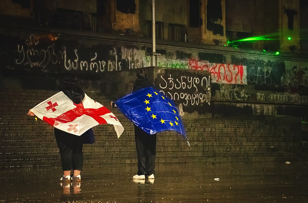 Protesta dalībnieces ar Gruzijas un Eiropas Savienības karogiem pie Gruzijas parlamenta 2024. gada decembrī.
