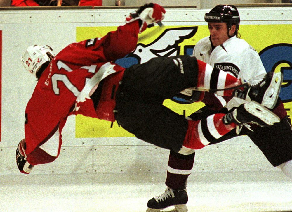 Latvijas izlases leģendārā spēle 1997. gada 30. aprīlī Turku pilsētā pret Kanādu – aizsargs Artūrs Kupaks (no labās) liek lidot pa gaisu kanādiešu uzbrucējam Bobam Erejam.