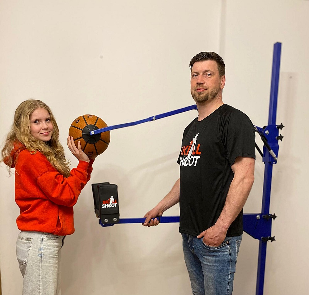 Jānis Gremzde ar meitu Skārletu pie basketbola metiena trenažiera.