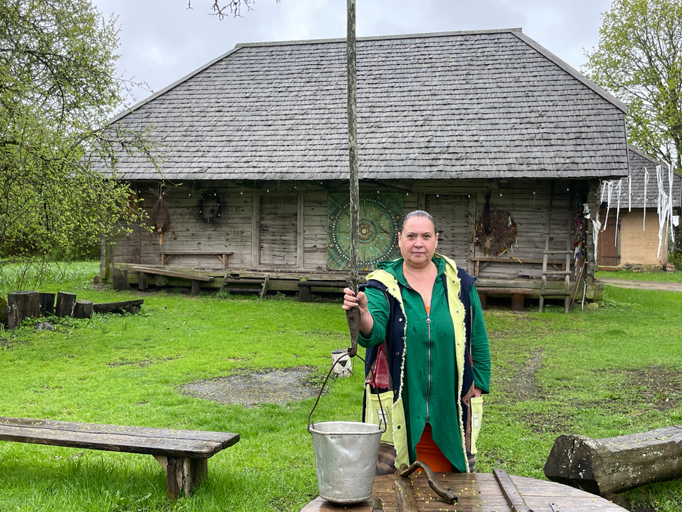 Kristīne Sīle savā “Evertu” sētā, viņai aiz muguras senākā ēka – klēts.