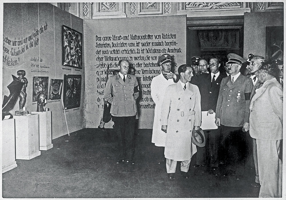 Hitlers Deģeneratīvās mākslas izstādē Minhenē. No Hitlera pa labi – profesors Cīglers un Heinrihs Hofmans, pa kreisi Haušs, Gebelss u. c. 1937. gada 19. jūlijs.