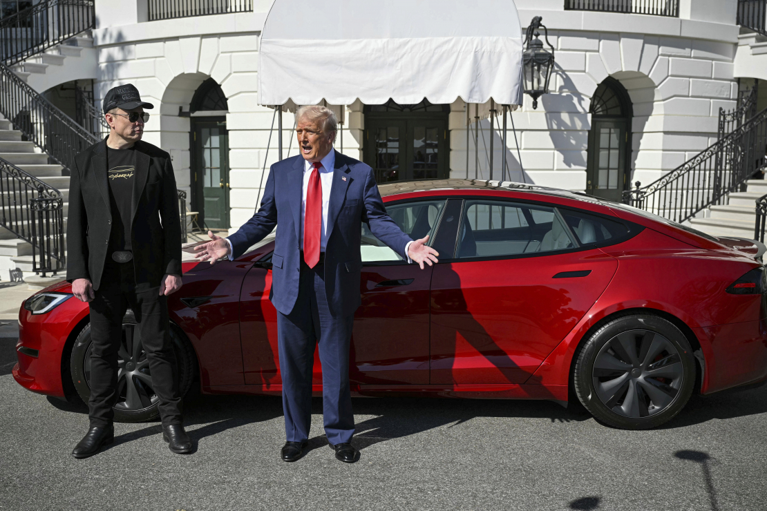 Prezidents Donalds Tramps un "Tesla" izpilddirektors Īlons Masks runā ar reportieriem pie sarkanas "Tesla Model S" automašīnas Baltā nama Dienvidu zālienā, otrdien, 2025. gada 11. martā, Vašingtonā.