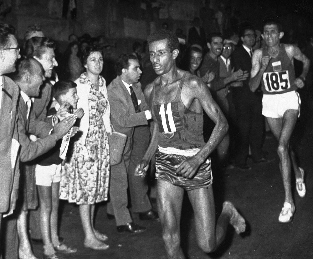Baskājainais Abebe Bikila Romas olimpiskajā maratonā priekšā marokānim Rhadi ben Abdesalamam. Etiopietis kļuva par pirmo un vienīgo skrējēju moderno olimpisko spēļu vēsturē, kurš maratonā uzvarējis, skrienot bez apaviem.