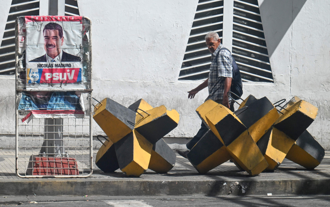 Vīrietis iet garām Venecuēlas prezidenta Nikolasa Maduro plakātam un prettanku barjerai Karakasā, 2025. gada 28. oktobrī. ASV spēki nogalināja 14 cilvēkus triecienos, kas iznīcināja četras, kā tiek apgalvots, narkotiku kontrabandā iesaistītas laivas Klusā okeāna austrumu daļā, otrdien paziņoja aizsardzības ministrs Pīts Hegsets.