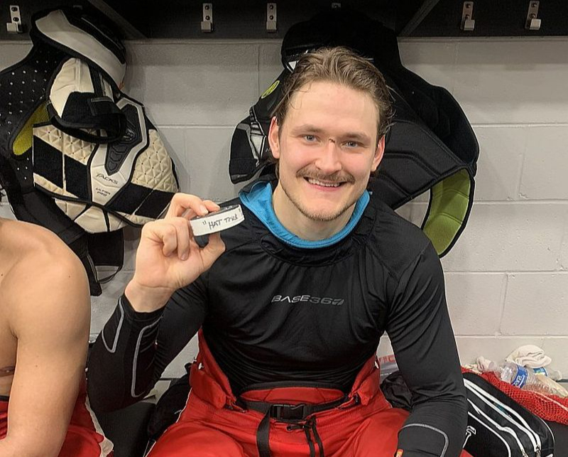 Smaidīgais Eduards Tralmaks pozē ar ripu pēc spēles, kurā viņš pirmo reizi savā profesionālajā karjerā Ziemeļamerikā guva trīs vārtus.