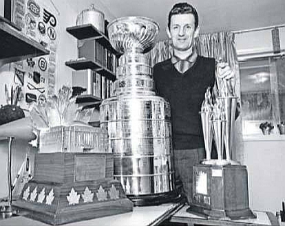 Toronto Hokeja slavas zāles kurators Moriss Reids pozē ar 1970. gadā nozagtajām un atgrieztajām trofejām – Kona Smaita balvu (no kreisās), Stenlija kausu un Billa Mastertona balvu.