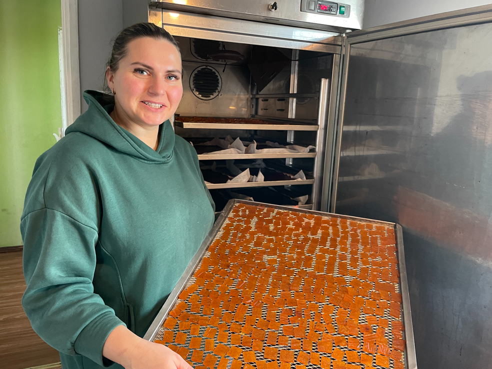 Dienu un nakti mājas virtuvē darbojas žāvētava. Attēlā: saimniece no žāvētavas izņem kārtējo gatavo konfekšu plāti.