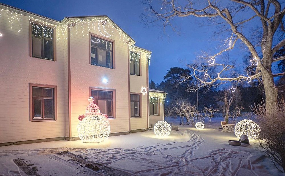 Saskaņojam gaismas virtenes ēkas greznošanai ar gaismas dekoriem dārzā.