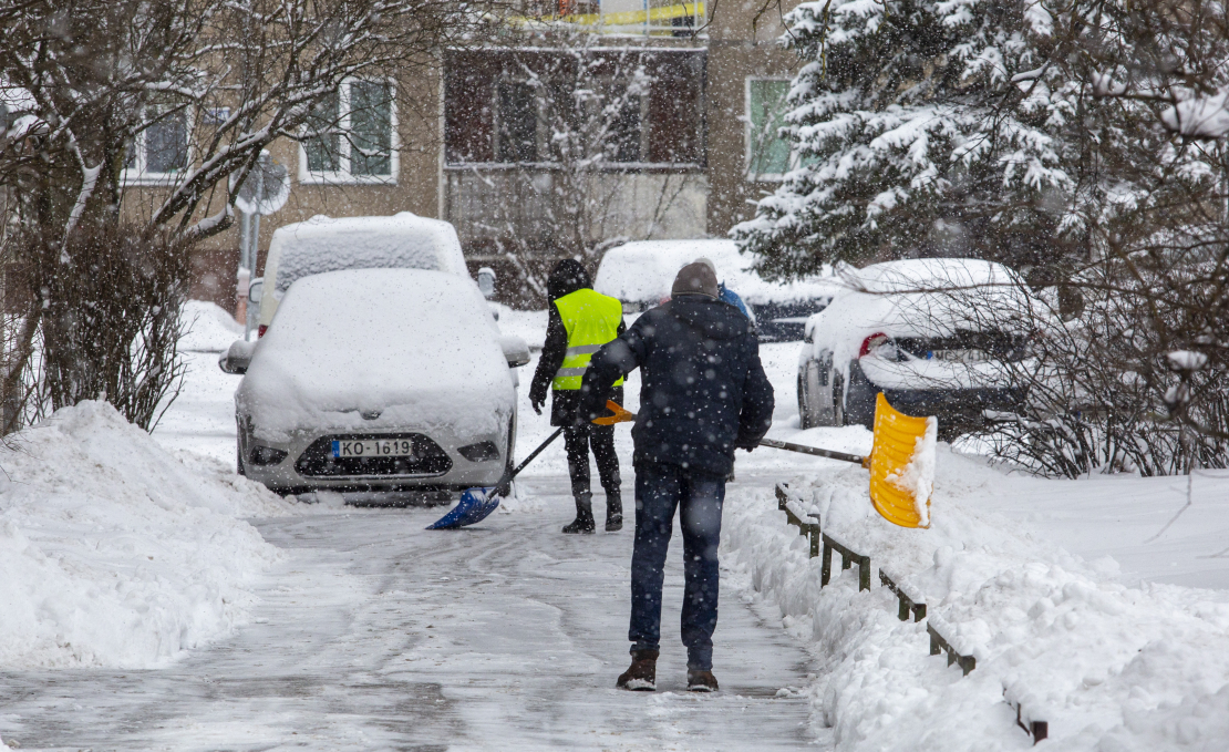Cilvēki tīra sniegu.