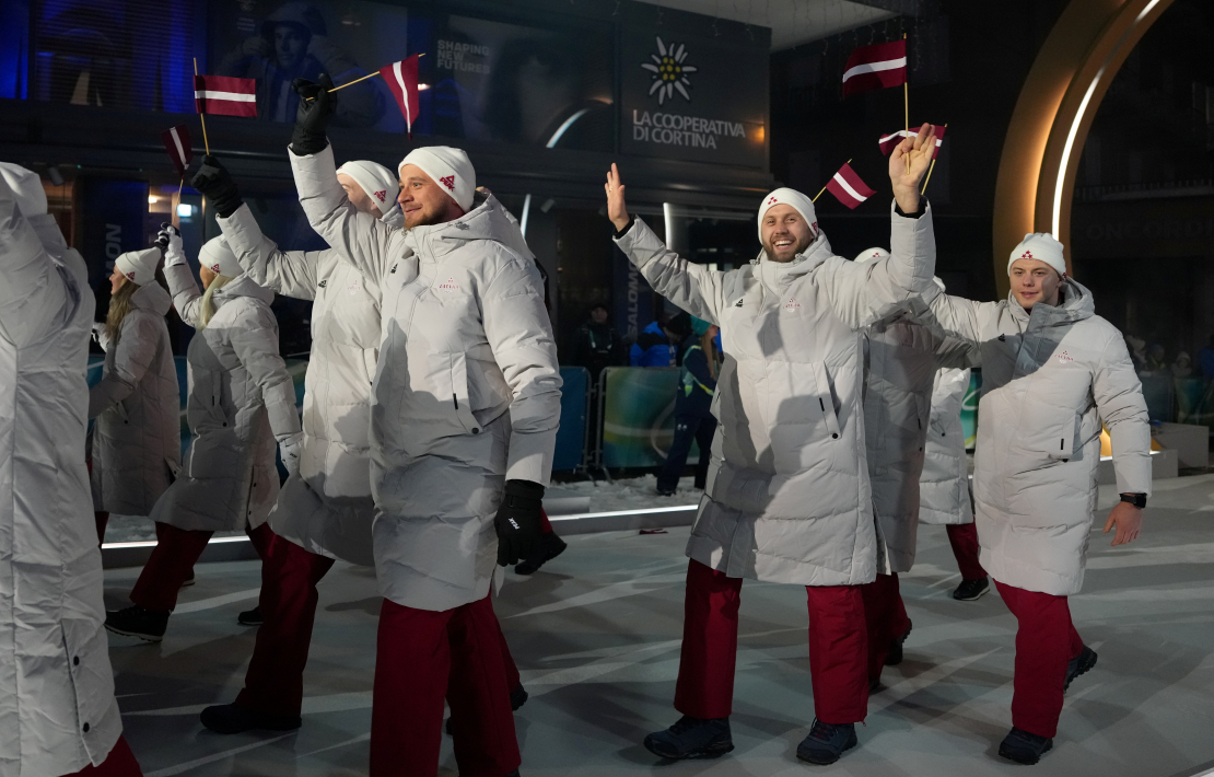 Latvijas karognesējs 2026. gada ziemas olimpiskajās spēlēs, hokejists Kaspars Daugaviņš (no labās) un Latvijas delegācijas sportisti 2026. gada Milānas un Kortīnas ziemas olimpisko spēļu atklāšanas ceremonijā "San Siro" stadionā Milānā, Itālijā.