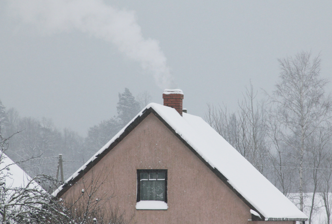 Māja ar kūpošu skursteni ziemā.