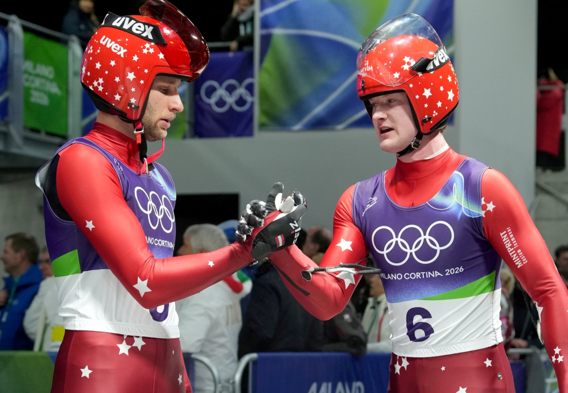 Latvijas kamaniņu divnieks Roberts Plūme (no kreisās) un Mārtiņš Bots sacensībās kamaniņās bobsleja, kamaniņu un skeletona trasē Kortīnā 2026. gada Milānas un Kortīnas ziemas olimpiskajās spēlēs Itālijā.