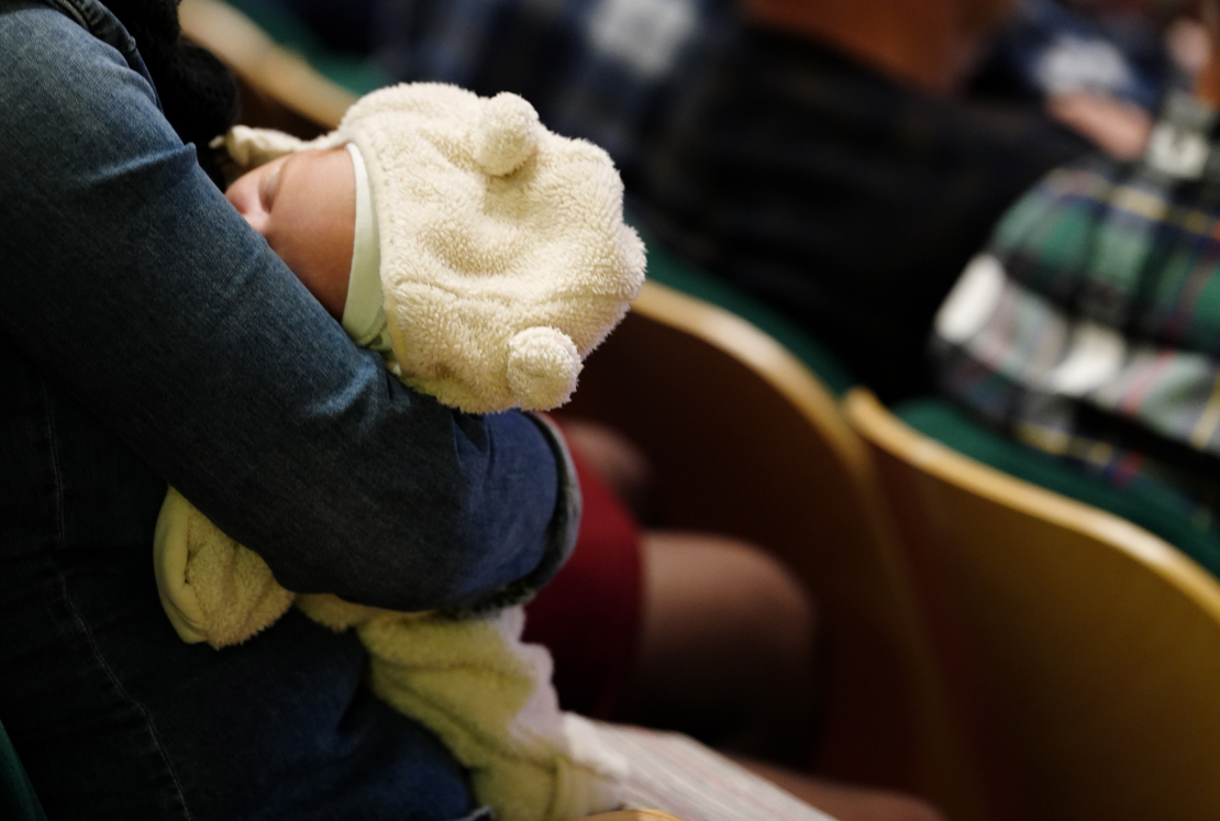 Zīdainis vecāka rokās.