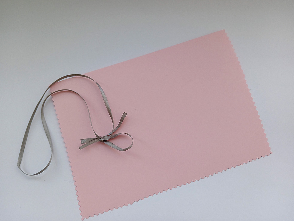 5. Atliek kartītē ievietot tāpat uz pusēm salocītu rozā papīra lapu un abas puses pārsiet ar šauru lentīti.  