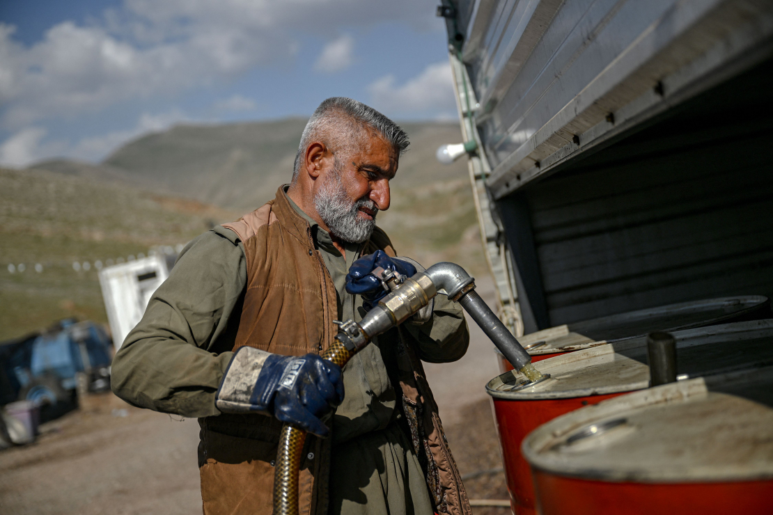 Tirgotājs pie Bašmahas robežšķērsošanas punkta 2026. gada 11. martā sūknē benzīnu no Irānas degvielas tankkuģiem tālākpārdošanai.